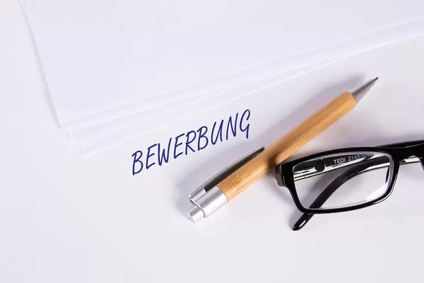 Stack of papers with pen, glasses and Bewerbung text