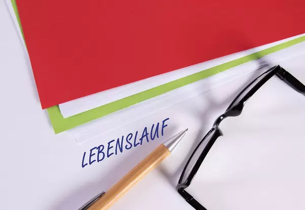 Stack of papers with pen, glasses and Lebenslauf text