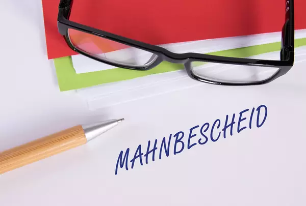 Stack of papers with pen, glasses and Mahnbescheid text