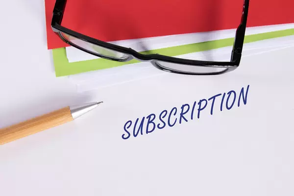Stack of papers with pen, glasses and Subscription text