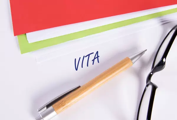 Stack of papers with pen, glasses and Vita text