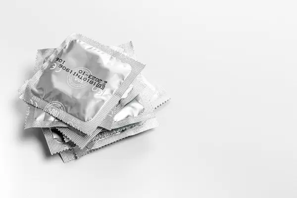Stack of sealed condoms on a white background