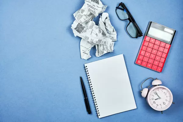 Stack of shop checks, calculator, alarm clock and blank notepad with copy space