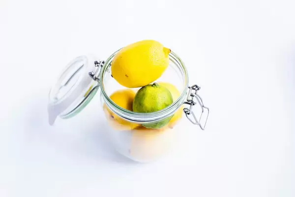 Stacked fresh lemons and lime in a metal jar on white background