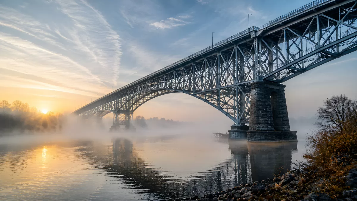 Stahlbrücke im Morgennebel bei Sonnenaufgang