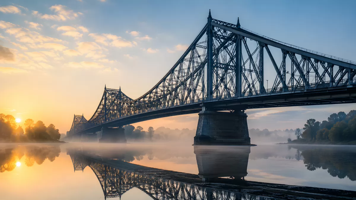 Stahlbrücke im Morgennebel über ruhigem Fluss