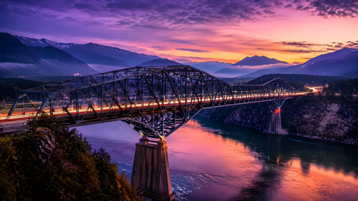 Stahlbrücke über Fluss bei dramatischem Sonnenuntergang