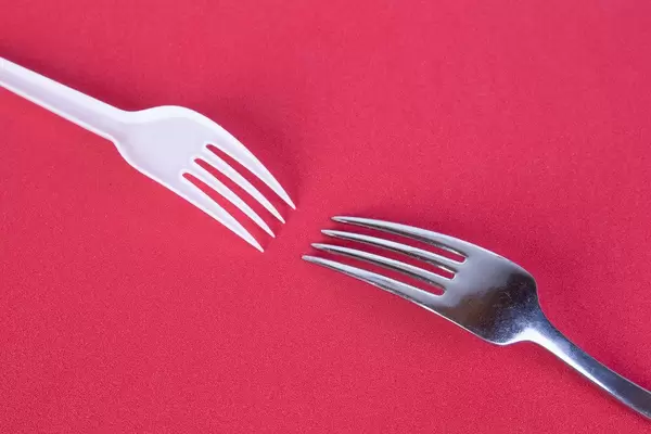 Stainless steel and plastic fork on red background