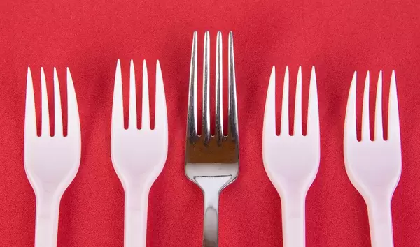 Stainless steel and plastic forks on red background