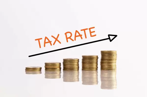 Stapel aus Münzen mit Pfeil und dem Text "Tax Rate" (Steuersatz)