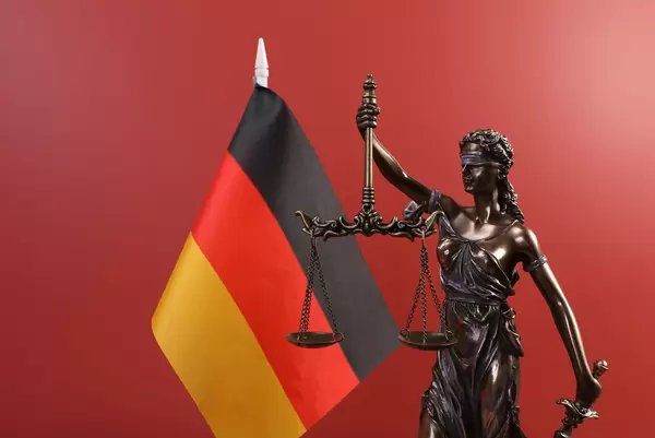 Statue of Lady Justice and flag of Germany on red background