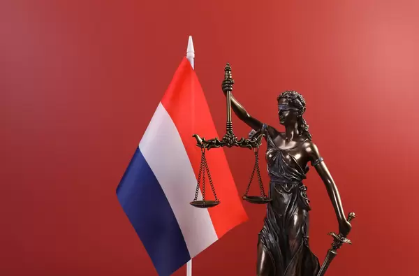 Statue of Lady Justice and flag of Netherlands on red background