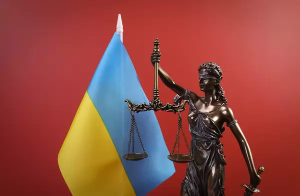 Statue of Lady Justice and flag of Ukraine on red background