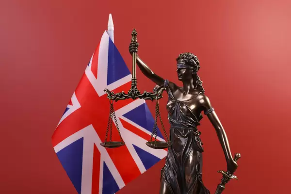 Statue of Lady Justice and flag of United Kingdom on red background