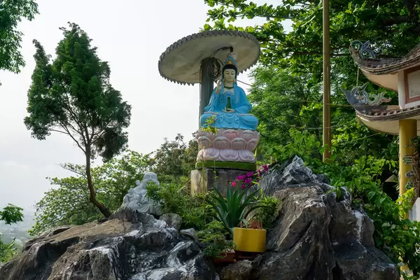 Statue of Sitting Lady Buddha and Laughing Buddha on a Small Rock in front of Tam Ton Pagoda at Marble Mountains in Da Nang, Vietnam