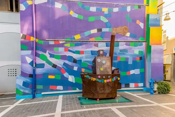 Statue of small ship in front of graffiti