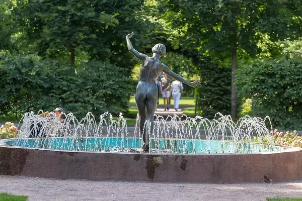 Statue of woman with naked butt in the middle of a round fountain in a park