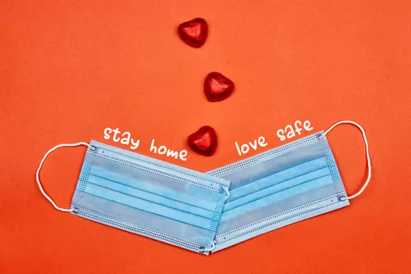 Stay home - Love Safe. Two face masks and sweets on red