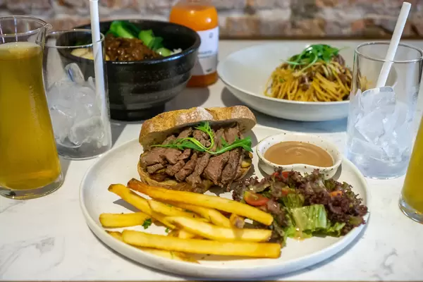 Steak Sandwich mit Pommes und Salat, Spaghetti Bolognese Taiwanesische Reis-Bowl mit Geschmortem Schweinefleisch und Getränke auf einem Restaurant Tisch