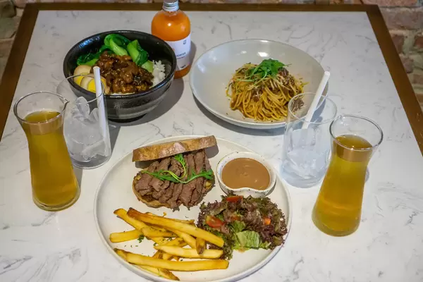 Steak Sandwich with French Fries and Salad, Spaghetti Bolognese, Taiwanese Braised Pork Bowl, Iced Tea and Fresh Juice on a Restaurant Table