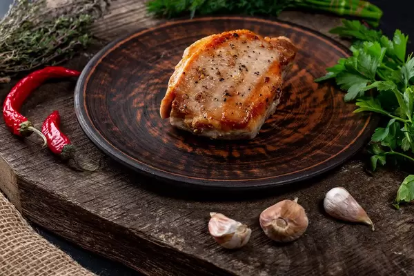 Steakteller mit Koriander, Knoblauch und Chili Paprika auf einem Holztisch