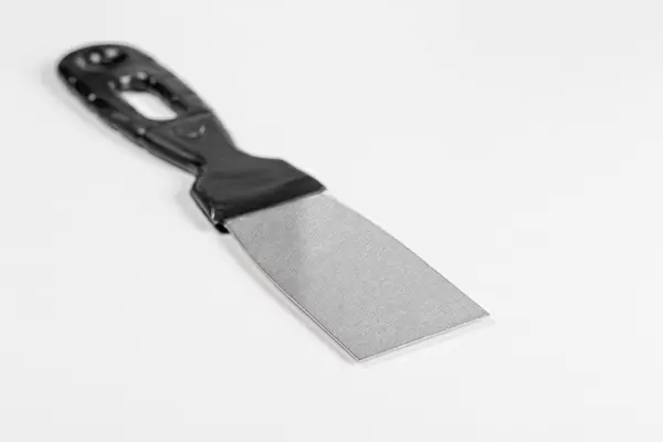 Steel trowel scraper with rubber handle on white background