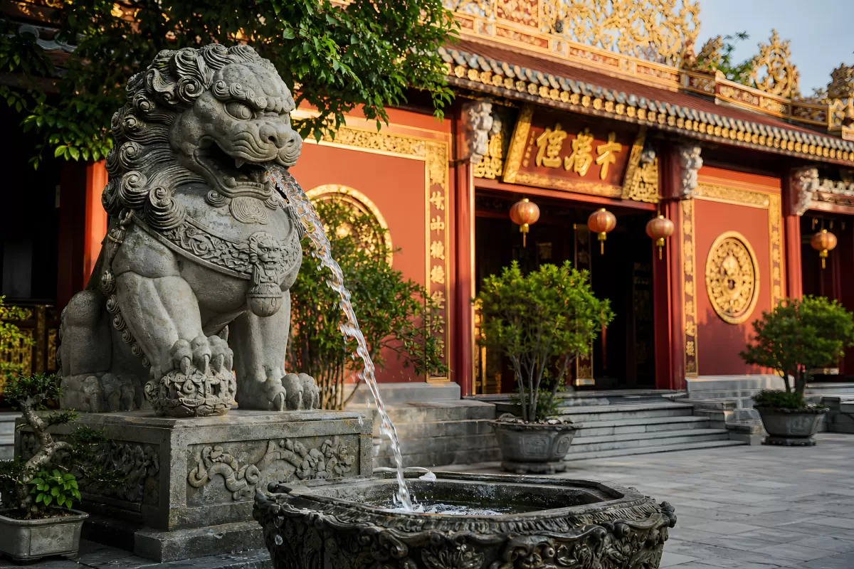 Steinlöwe als Brunnen vor rotem chinesischen Tempel