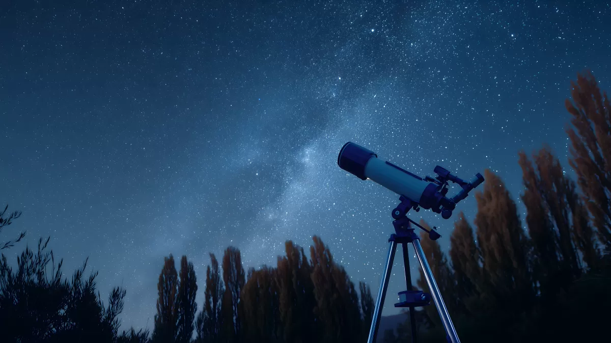 Sternenhimmel und astronomisches Teleskop bei Nacht