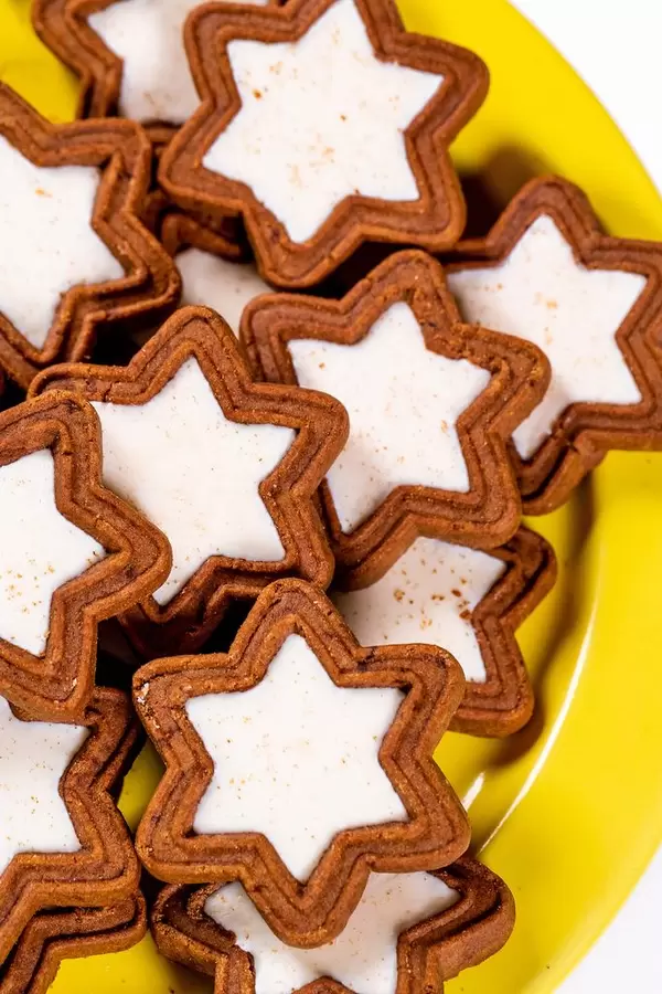 Sternförmige Weihnachtskekse mit Schokolade und weißer Füllung auf gelbem Teller