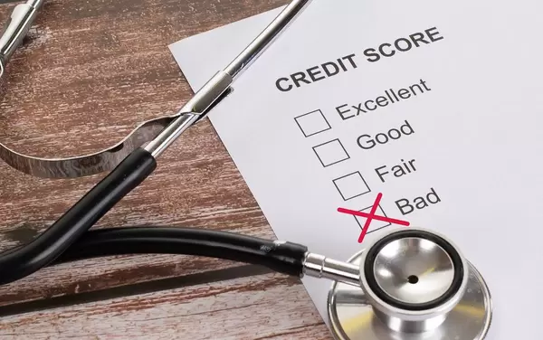 Stethoscope and bad credit score result on wooden table