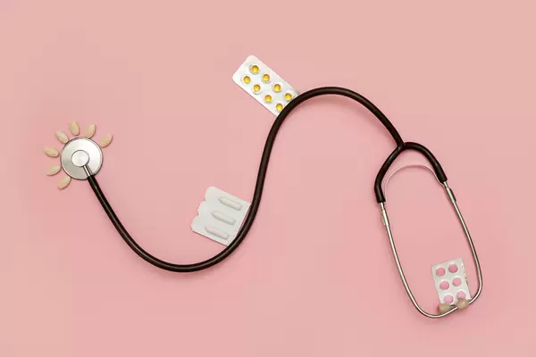 Stethoscope and medicines on bright pink background