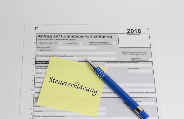 Steuererklärung 2018: Unausgefüllter Lohneteuer-Antrag unter Notizzettel und blauen Kugelschreiber - Nahaufnahme in Draufsicht