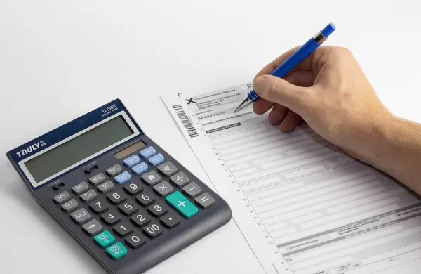 Steuererklärung wird ausgefüllt mit einem Taschenrechner auf einem Tisch