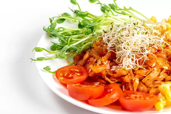 Stewed cabbage with micro-green onions, peas and tomato slices