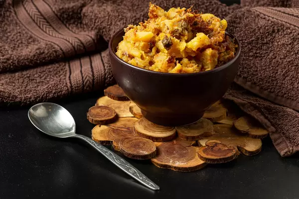 Stewed potatoes with vegetables and meat on a dark background