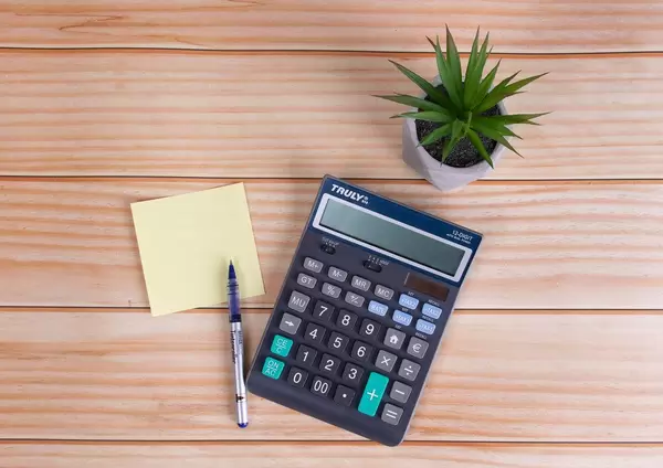 Sticky note, pencil and calculator on wooden table
