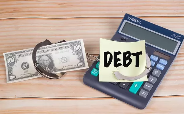 Sticky note with Debt text in handcuffs on calculator