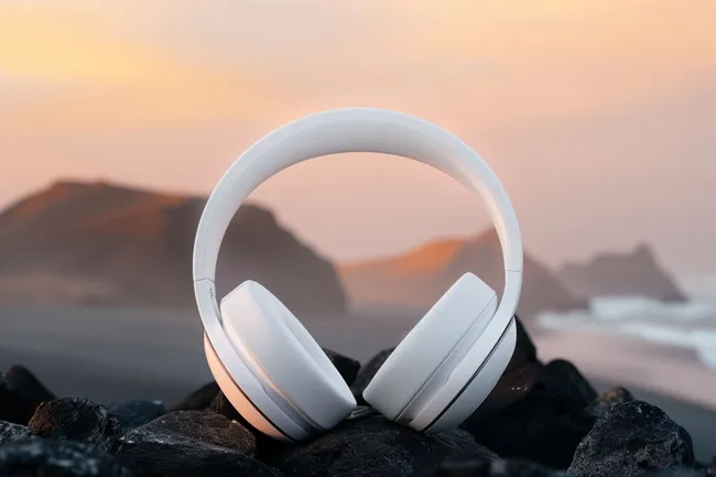 Stilvolles weißes Over-Ear-Headset vor malerischer Küstenlandschaft