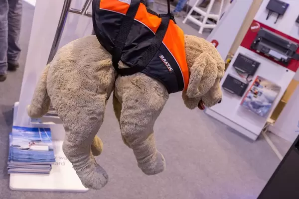 Stoffhund trägt orange-schwarze Schwimmweste für Hunde von Baltic und hängt an Haltegriff