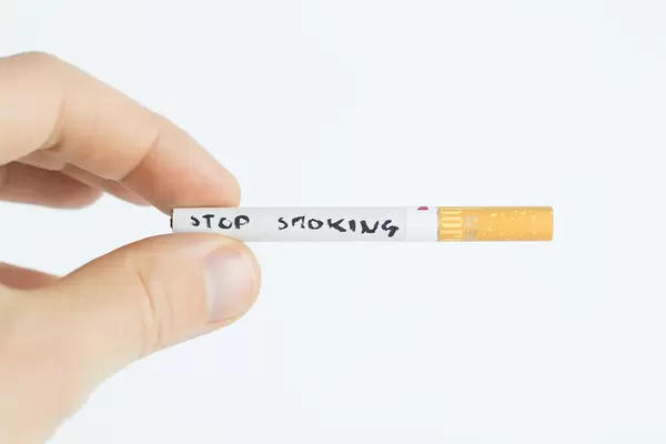 Stop smoking written on a cigarette and held by a man's hand