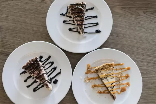 Stracciatella Schoko-Torten un Karamelltoretn Stücke mit Topping auf weißen Tellern - Aufnahme von oben