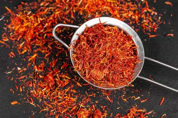 Strainer with scattered dried saffron on black