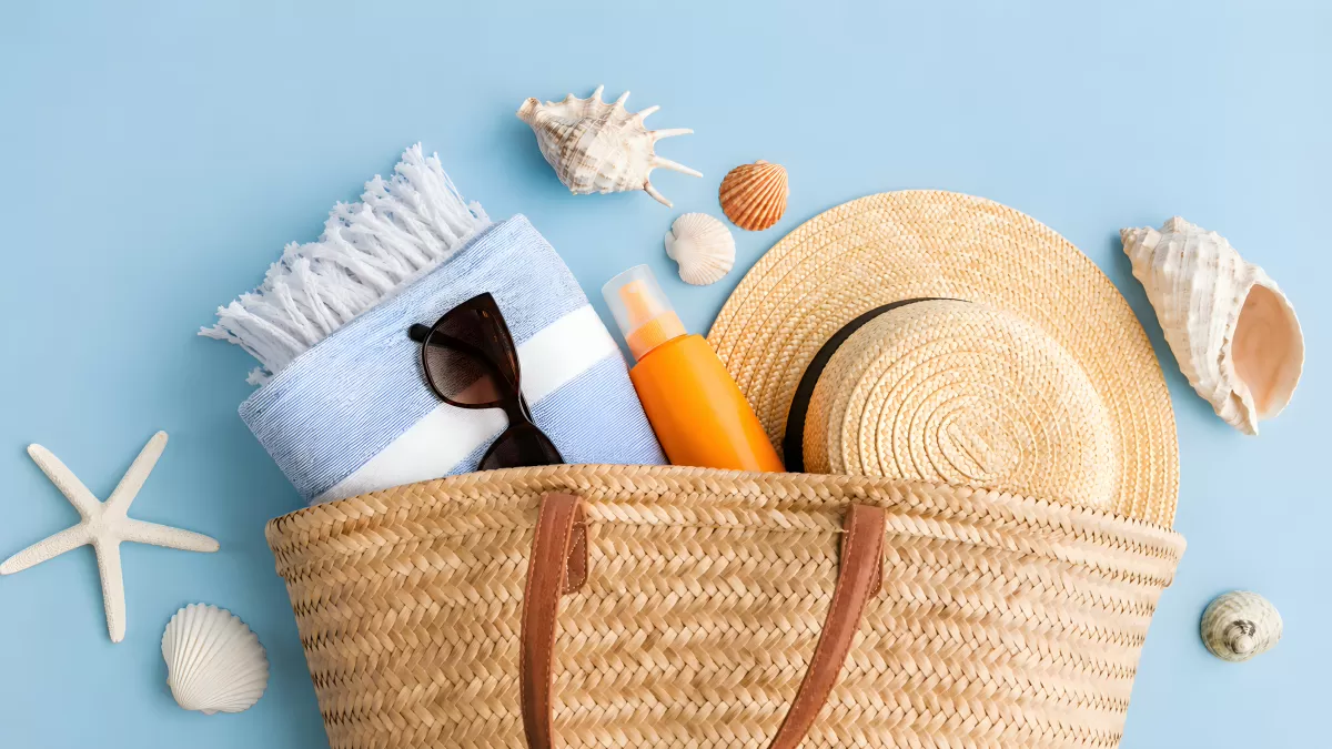 Strandtasche mit Sonnencreme, Hut und Muscheln