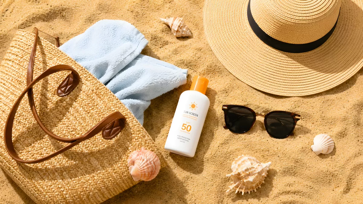 Strandtasche mit Sonnencreme und Sommerzubehör im Sand
