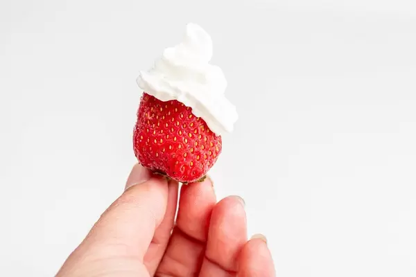 Strawberries with whipped cream in a woman's hand