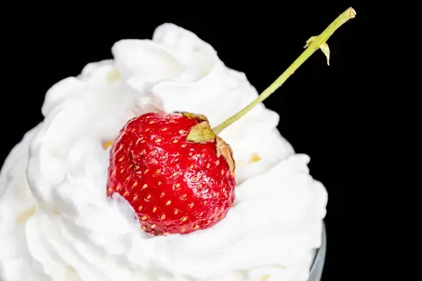 Strawberries with whipped cream on a dark background