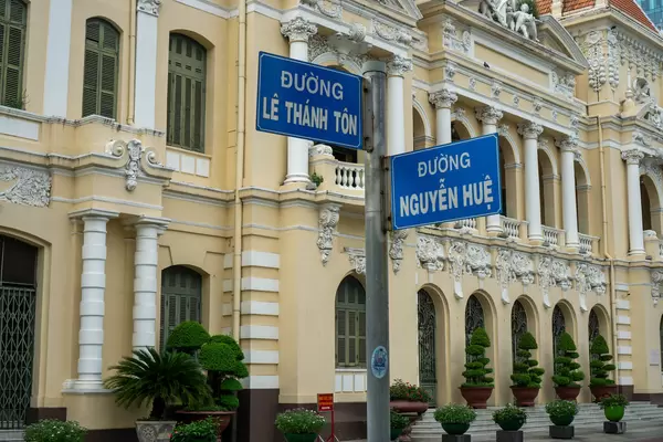 Street Signs of Intersection of Nguyen Hue and Le Thanh Ton Street with People's Committee of Ho Chi Minh City, Vietnam in the Background