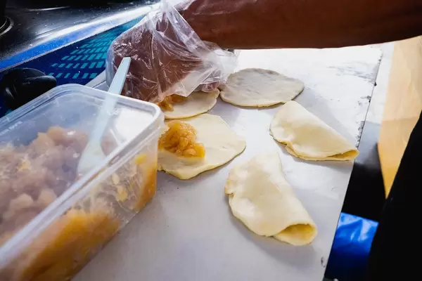 Street vendor placing fillings of an empanada