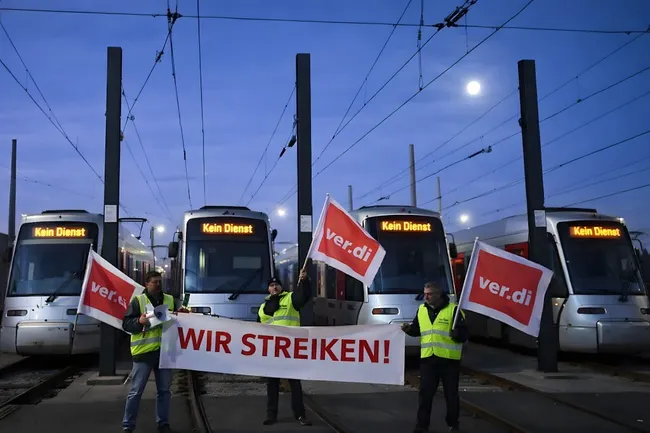 Streikende Gewerkschaftsmitglieder mit Ver.di-Fahnen vor Straßenbahnen