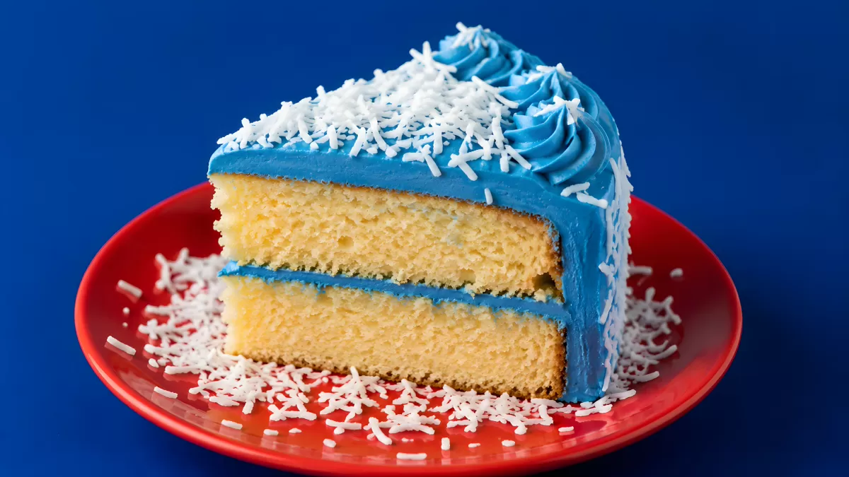 Stück Geburtstagstorte mit blauer Buttercreme und Streuseln